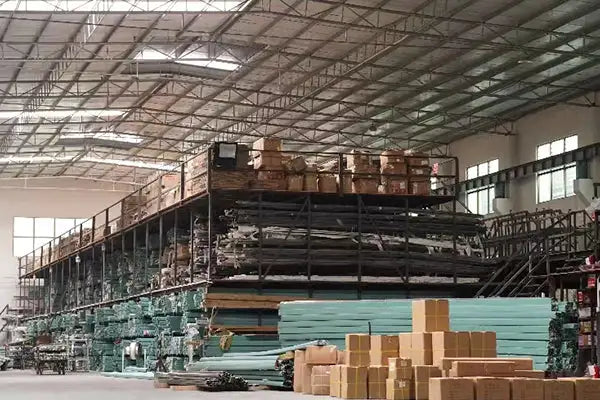 The image shows a large industrial warehouse with multiple levels of metal shelving units stacked high, holding various materials and products.