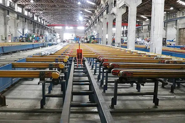 Yellow-painted metal beams arranged in rows on industrial racks within a factory setting.